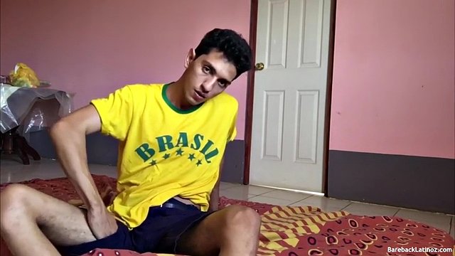 On the bed, Santiago slowly strips down to his underwear, working hard to get his big uncut cock hard. He then pulls that hard-on from the leg of his boxers and plays with it. On his back, a slender and sleek boy starts jerking off.